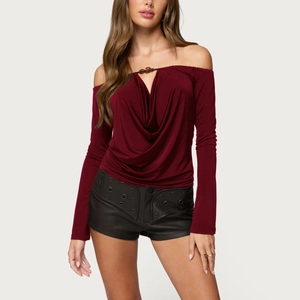 Detail of burgundy off-shoulder top featuring draped neckline and knot embellishment