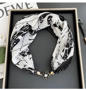 Close-up of pleated black and white silk scarf with a pearl flower magnetic buckle