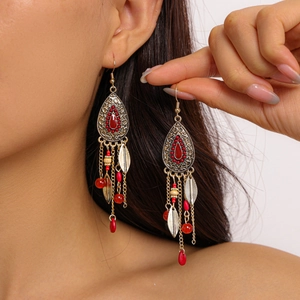 Macro detail of vintage bohemian earrings with red beads and dangling metal leaves