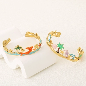Detail of gold ocean-themed cuff bangles with colorful enamel starfish and palm tree charms