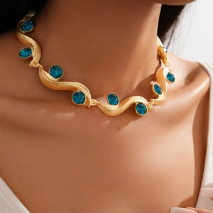 Close-up of vintage gold wavy necklace with blue gemstone inlays on model neck