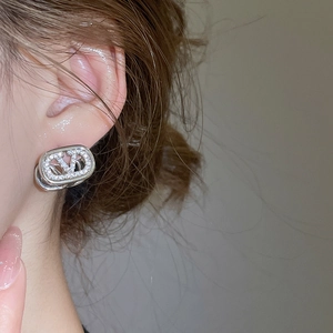 Detail of silver V-logo earrings with micro-set zircons worn by a female model