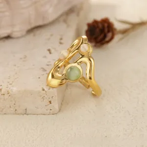 Detailed close-up of a gold wavy open ring with light green opal and clear stones