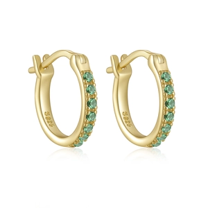 Macro detail of S925 sterling silver stamp and green cubic zirconia on gold hoop earrings