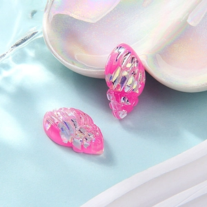 Macro shot of two pink resin seashell charms with iridescent glitter on a white plate