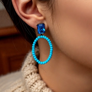 Close-up of vintage oval hollow earrings with blue gemstones and turquoise beads
