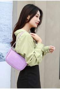 Close-up of light purple hobo bag with crocodile texture worn by a model in a casual setting