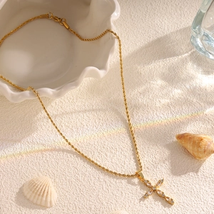 Close-up of golden rope chain necklace with sparkling diamond-encrusted cross pendant