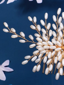 Detail of handmade gold bridal hair comb featuring white pearls and leaf structure