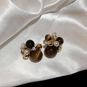 Detailed shot of vintage gold stud earrings with brown cat-eye stones and white pearls
