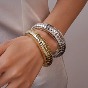 Close-up of gold and silver chunky textured acrylic bracelets on a model's wrist