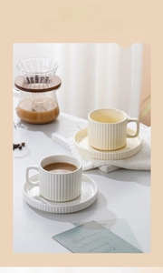 Detail view of cream-colored ceramic coffee cups with vintage vertical ribbed patterns