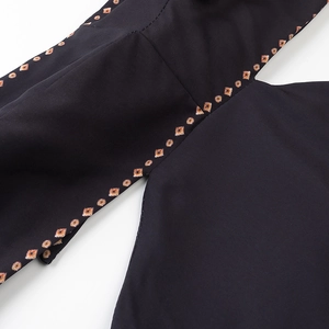 Detail shot of the waist cutout design and orange geometric print on the black maxi dress