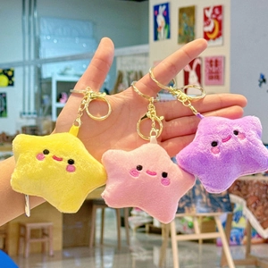 Handheld display of cute plush star keychains with smiling faces in yellow, pink and purple