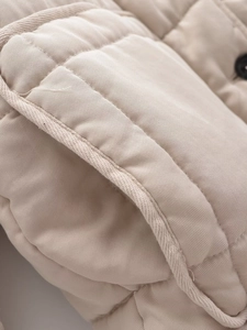 Macro view of beige quilted cotton jacket featuring fine stitching and button details