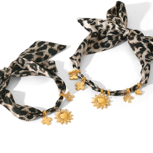 Leopard print scrunchies set with gold sun, butterfly, and tree charms on white background