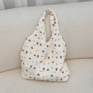 Détail du sac cabas gaufré blanc cassé avec imprimé Bread Dog sur un canapé doux