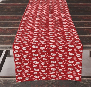 Detail of red Christmas table runner with masked Santa Claus and Ho Ho Ho patterns