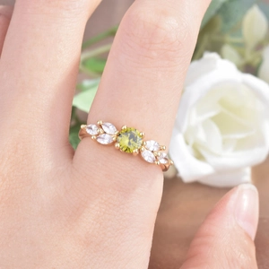Macro shot of gold ring with olive green round zircon and marquise-cut side stones