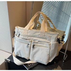 Detail view of large corduroy shoulder bag in cream white with adjustable strap and pockets