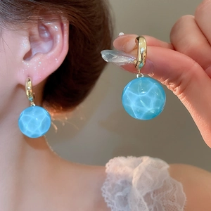 Détail de boucles d'oreilles créatives avec boule d'eau bleue et anneau doré