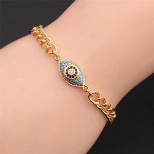 Dettaglio di un bracciale a catena dorata con ciondolo malocchio blu e nero in zirconi