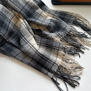 Close-up of black and white checkered scarf featuring soft fringed tassels and texture