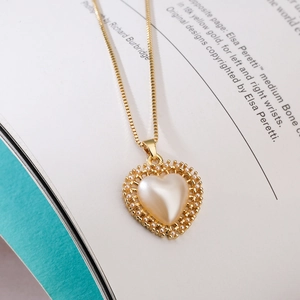 Macro view of 18K gold plated heart pendant with pearl inlay on an open book page