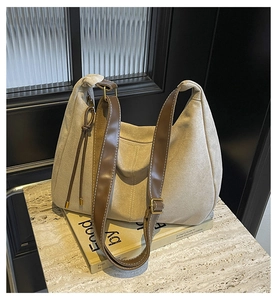 Close-up of beige suede tote bag with brown leather strap on a decorative book
