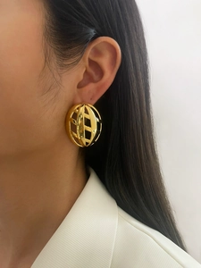 Close-up of a hollow geometric gold earring with metallic luster on model ear