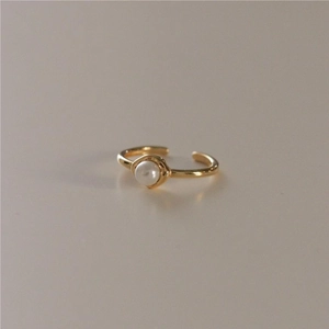 Elegant gold 925 silver open ring with white pearl on a minimalist beige background