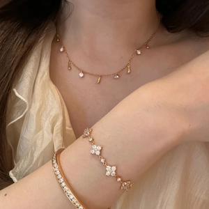 Detailed view of layered gold-tone necklace set with crystal cross pendant and clover bracelet
