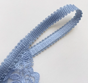 Close-up of light blue floral lace embroidery and elastic scalloped strap detail