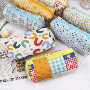 Detailed view of quilted cotton cosmetic bags in various patterns with metal zippers