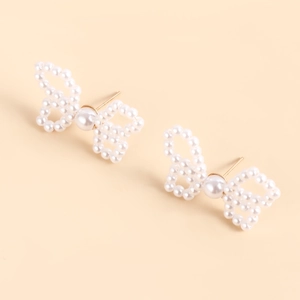 Detail of handmade bow knot pearl earrings with elegant white beads and golden pins