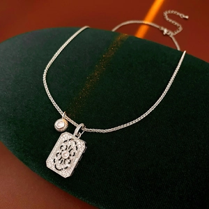 Detailed macro view of silver-toned hollow rectangular zircon pendant on velvet