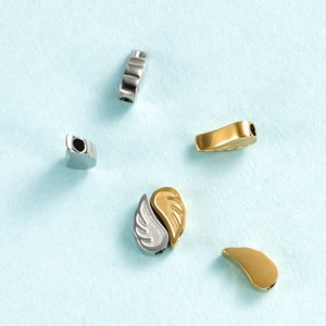 Detailed view of angel wing charms and spacer beads in gold and silver stainless steel