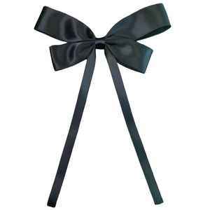 Close-up of elegant large black satin bow hair clip with long flowing ribbons on white