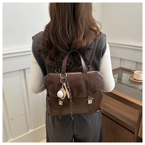 Détail du sac à dos en cuir marron vintage avec pendentif de baseball minimaliste