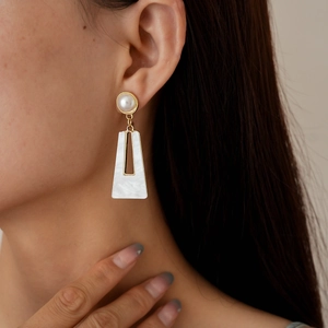 Detailed close-up of acrylic pearl earrings with geometric resin in gold frame
