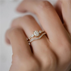 Close-up of emerald cut diamond engagement ring with matching gold V-shaped band