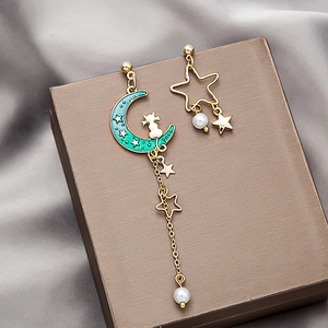 Elegant asymmetrical cat and moon tassel earrings with pearls on silk background