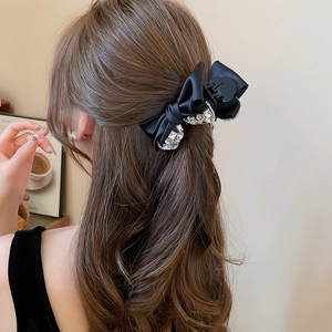 Dettaglio della clip per capelli a fiocco in raso nero con strass su capelli ondulati