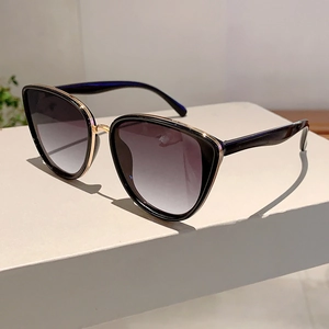 Detail of cat-eye sunglasses with gold metal trim and gradient lenses on a display stand