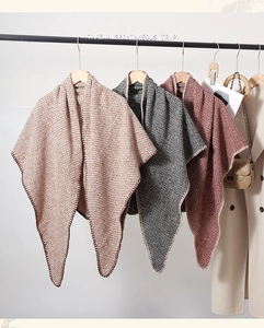 Detail of three houndstooth knit scarves in brown and black on wooden hangers