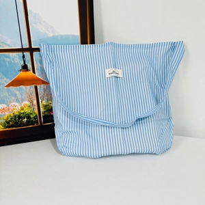 Detailed close-up of blue and white striped fabric tote bag on a minimalist desk