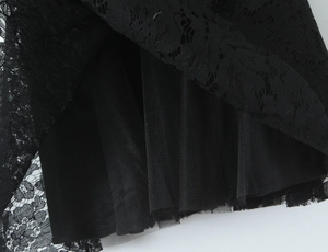 Close-up of black floral lace texture and layered mesh fabric on a summer dress