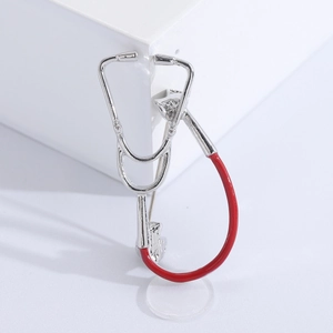Close-up of creative stethoscope brooch with silver metal finish and red tubing detail