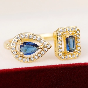 Detail of gold-plated open ring with blue stones on red velvet background