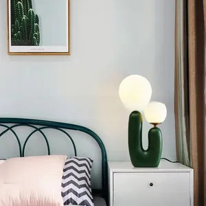 Detail of creative cactus lamp with dual frosted glass globes on a green matte base